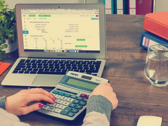 Notebook com uma planilha aberta e mãos numa calculadora sobre a mesa